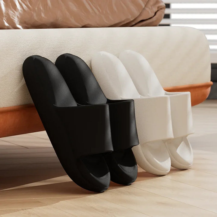 Black and white slippers on a wooden floor with a beige sofa in the background