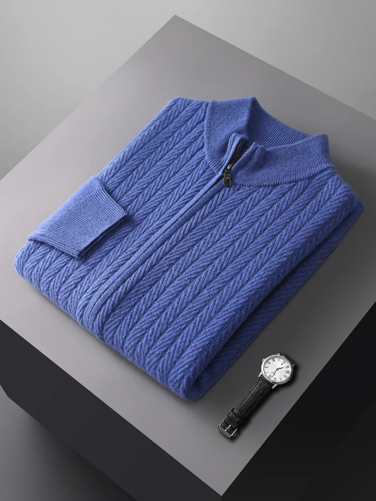 Folded blue sweater on a gray surface with a watch beside it