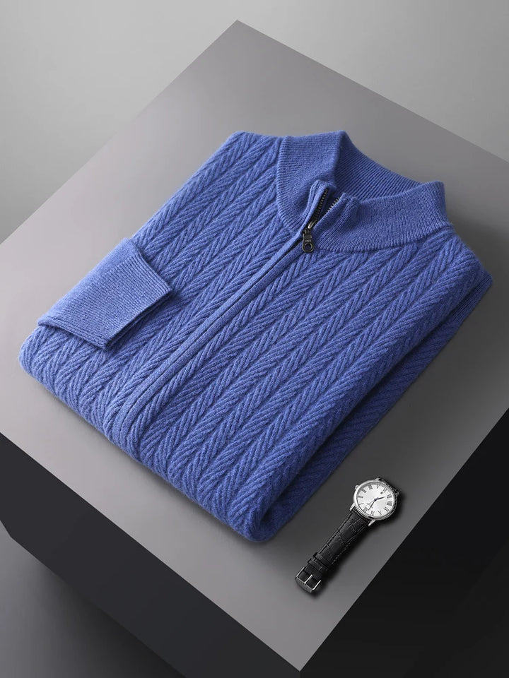 Folded blue sweater on a gray surface with a watch beside it