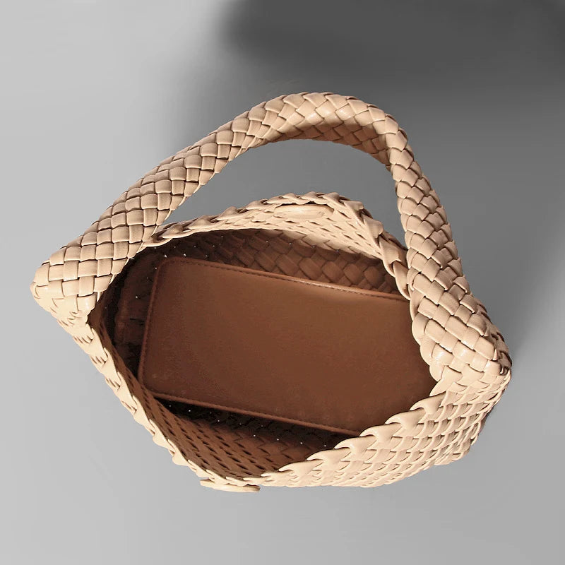Woven beige handbag with a brown interior on a gray background