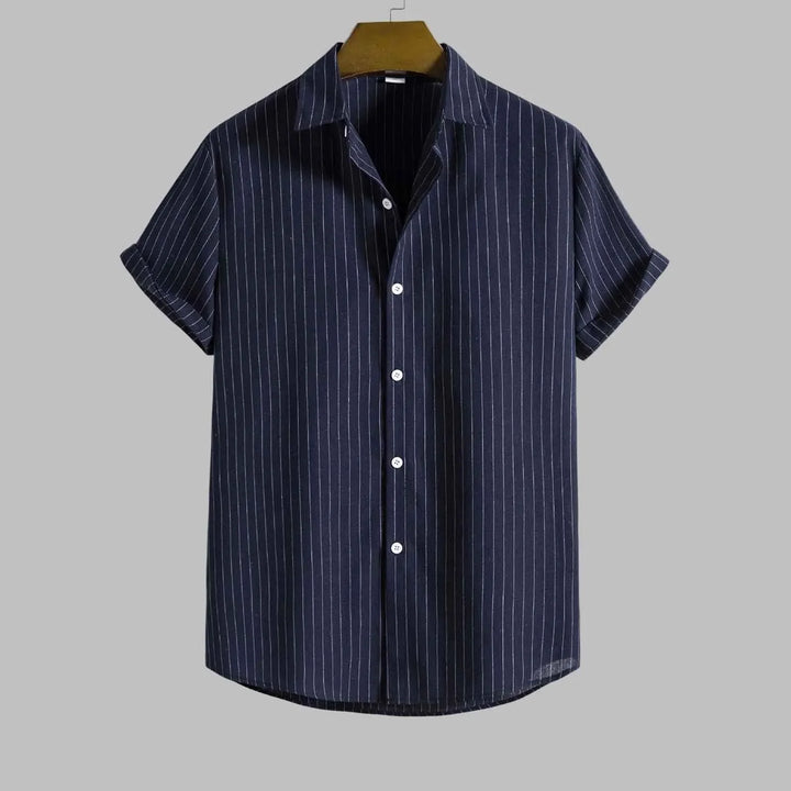 Navy striped shirt on a hanger against a gray background