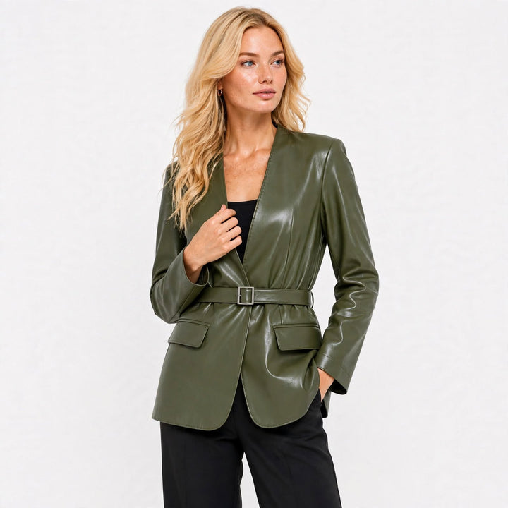 A woman modeling a shiny olive green leather blazer with a matching belt, styled over a black top and black pants against a plain white background.