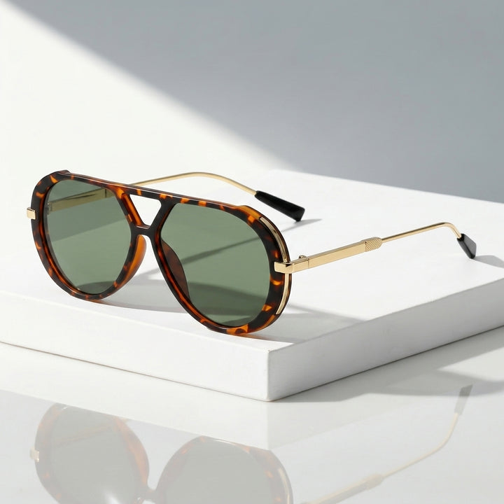 A pair of aviator-style sunglasses with tortoiseshell frames and green-tinted lenses, resting on a white rectangular display block against a light gray background.