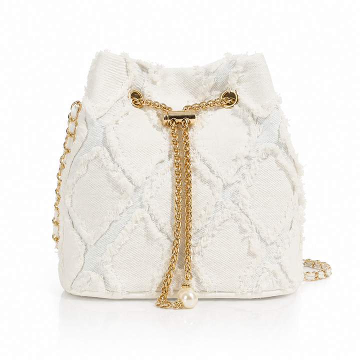 An off-white textured bucket bag with a gold-tone chain strap and a dangling pearl accent, set against a plain white background.